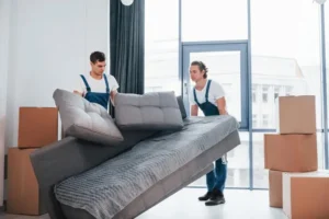carrying-heavy-sofa-two-young-movers-blue-uniform-working-indoors-room_146671-52053